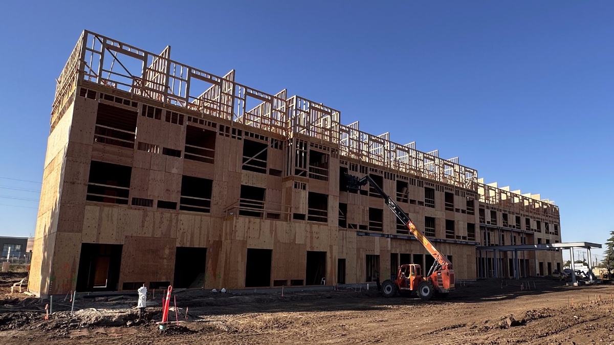 Framed building on site with telehandler in the foreground